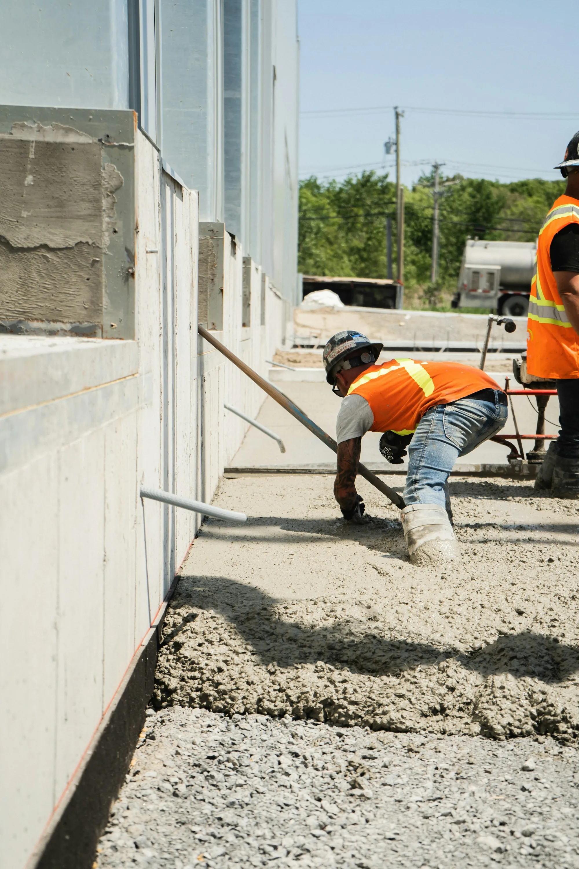 Worker spreading concrete along a foundation wall